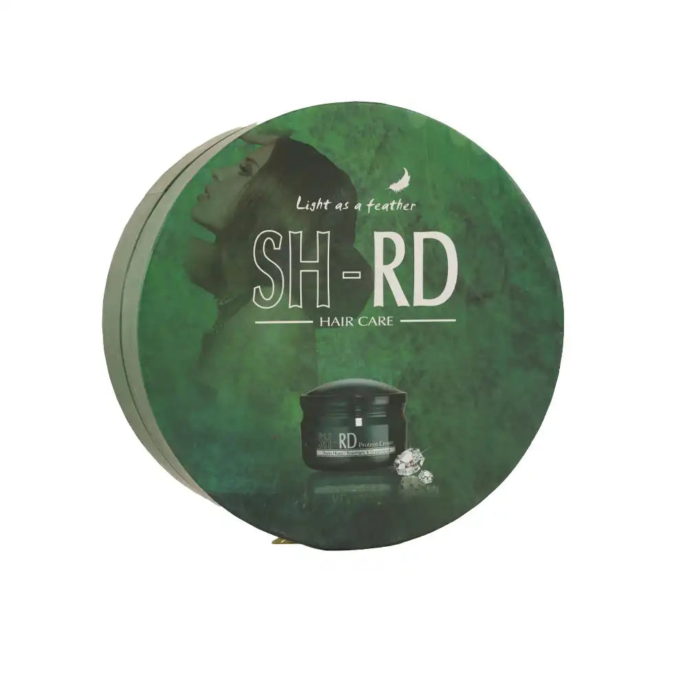 A round green product box for SH-RD Hair Care, featuring a dark silhouette of a woman's profile, white text, and a small image of a black hair care jar with crystals on the front, set against a plain white background.