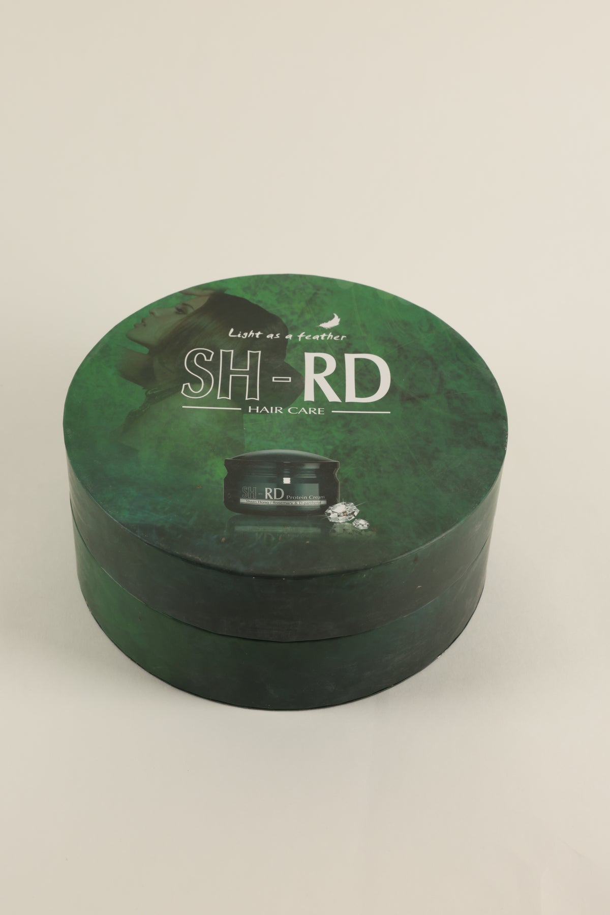 A round green SH-RD hair care product box with a lid, photographed on a plain light background.