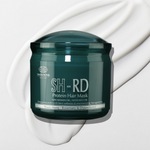 A dark teal-green jar of SH-RD Protein Hair Mask by SHAI HONG, shown on a white background with a white cream swirl behind it.