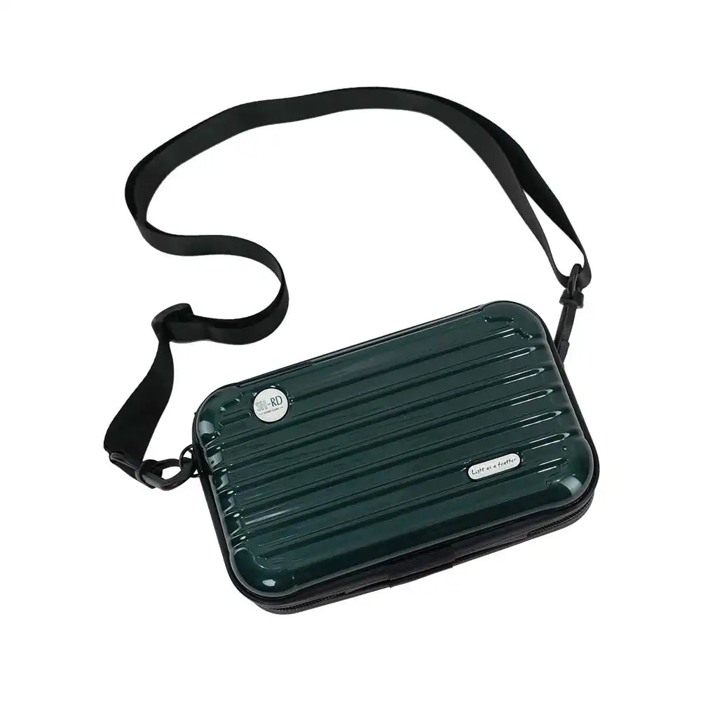 A dark green hard-shell crossbody bag with a black adjustable shoulder strap, featuring a ribbed texture and a small silver brand plaque.