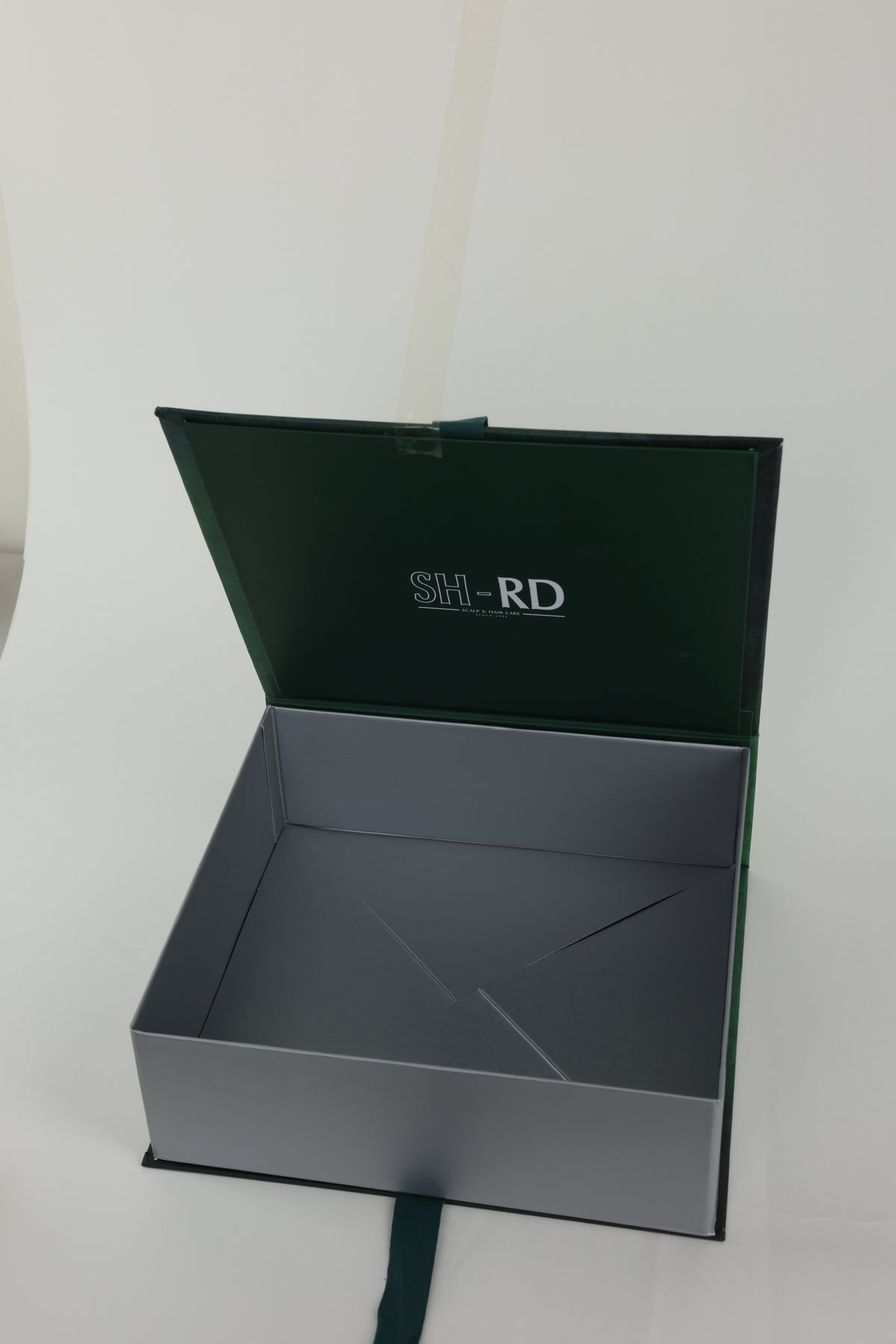 An open dark green and gray presentation box with the brand name 'SH-RD' printed on the inside lid, set against a plain light background.