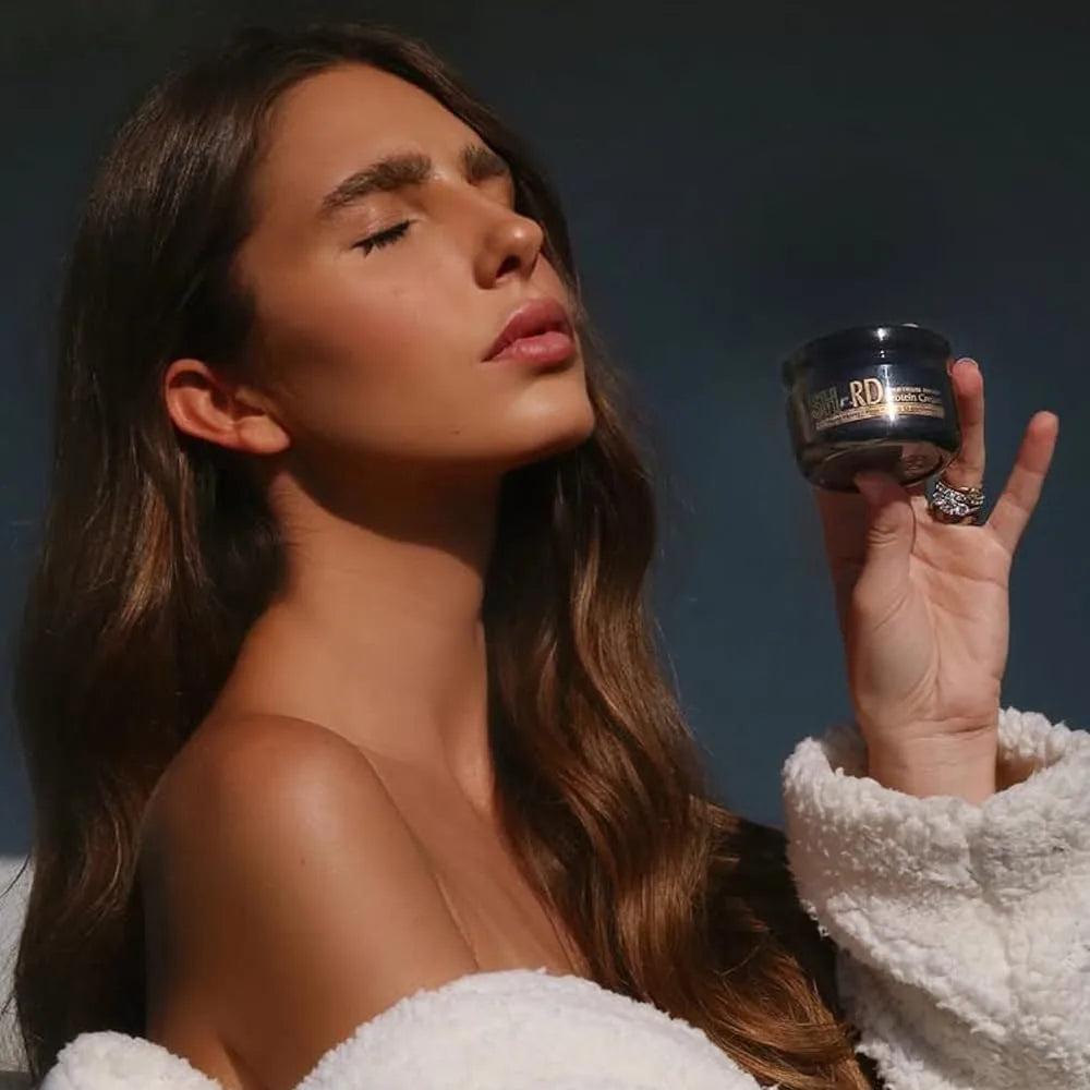 Woman holding a jar of skincare product against a dark background